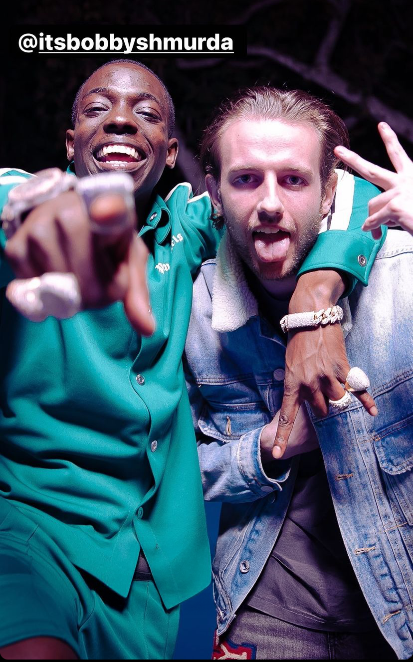 Two people posing together with one making a peace sign, wearing green and denim outfits.